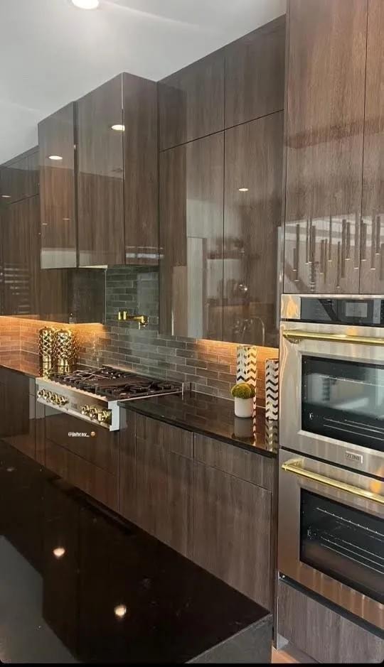 Chef's kitchen with dark walnut cabinetry, black granite countertops, and gold hardware
